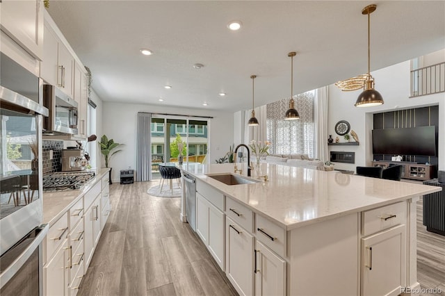17194 Desert Wine Ln, Parker, CO 80134 - kitchen with stainless steel appliances, open floor plan, light wood-style flooring, a kitchen island with sink, and white cabinets