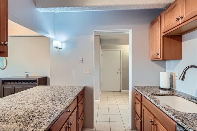 kitchen featuring light stone counters, sink, and light tile patterned floors