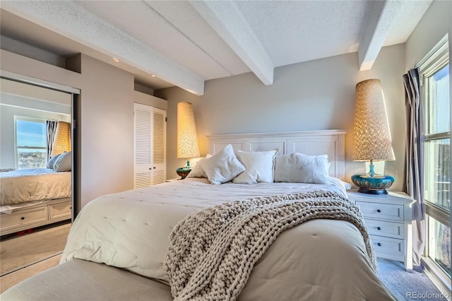 carpeted bedroom featuring beam ceiling, a closet, and a textured ceiling