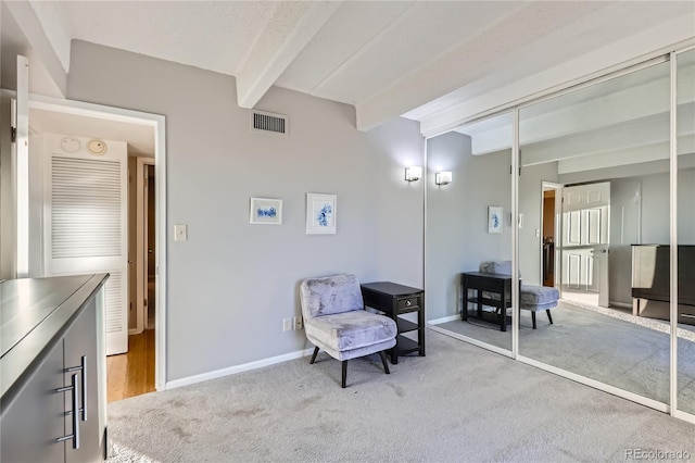 sitting room with light carpet and beamed ceiling