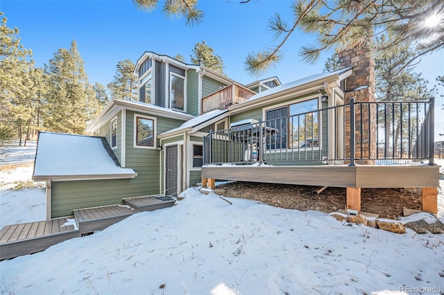 snow covered property featuring a balcony and a wooden deck