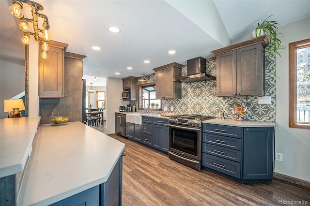 kitchen featuring dark hardwood / wood-style flooring, wall chimney exhaust hood, stainless steel appliances, vaulted ceiling, and pendant lighting