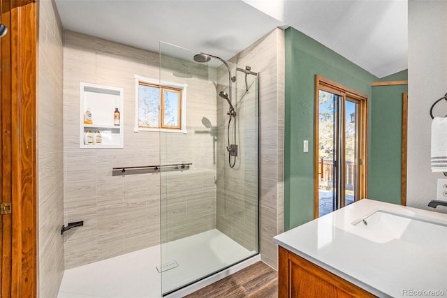 bathroom featuring tiled shower, hardwood / wood-style floors, vanity, and vaulted ceiling