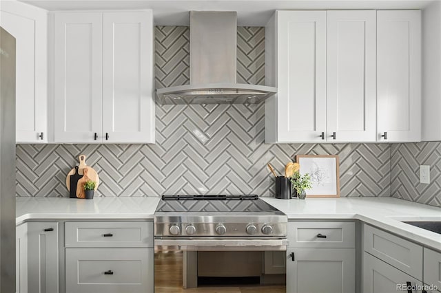 1755 Ingalls St, Lakewood, CO 80214 - kitchen featuring wall chimney range hood, stainless steel electric stove, tasteful backsplash, and white cabinets