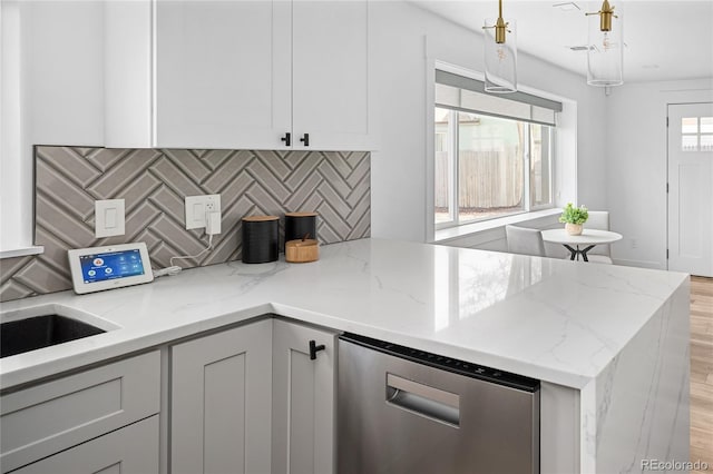 1755 Ingalls St, Lakewood, CO 80214 - kitchen with light wood-style flooring, tasteful backsplash, a peninsula, light stone countertops, and hanging light fixtures