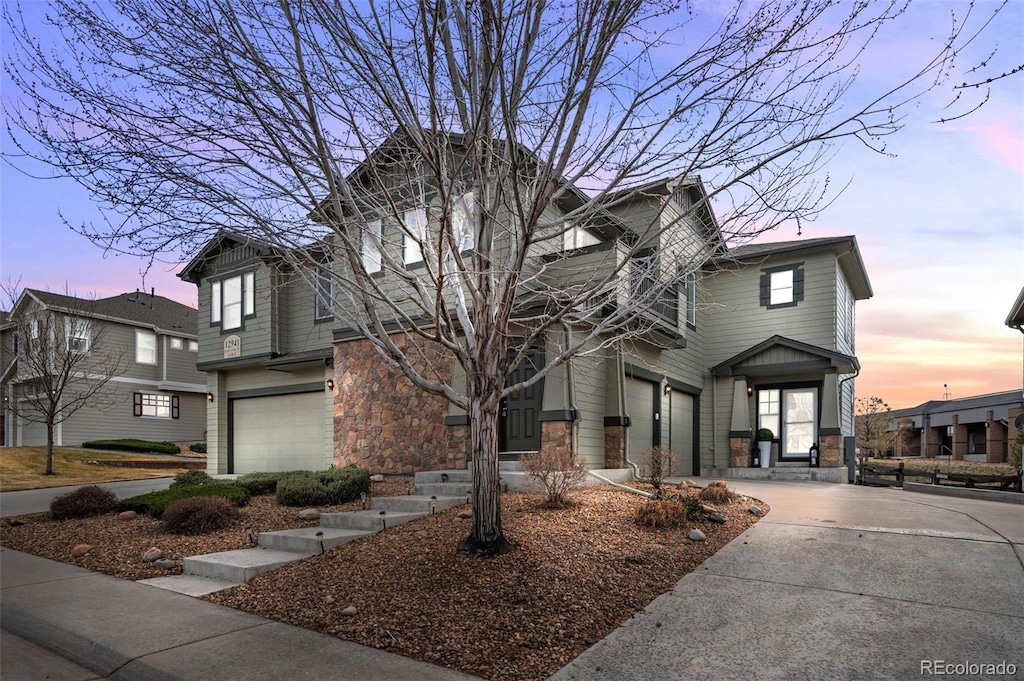 view of front of house featuring stone siding, an attached garage, and concrete driveway