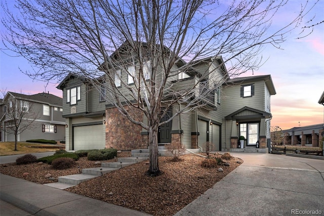 view of front of house featuring stone siding, an attached garage, and concrete driveway