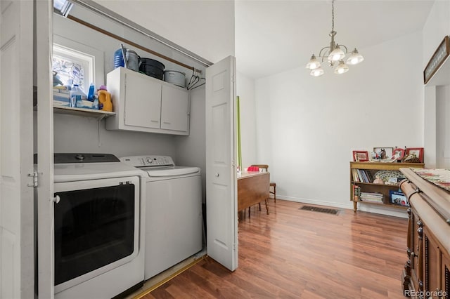 laundry room featuring dark hardwood / wood-style flooring, an inviting chandelier, cabinets, and washing machine and clothes dryer