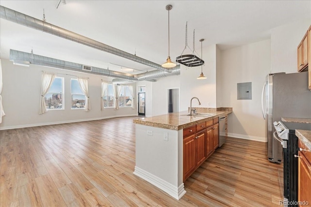 kitchen with brown cabinets, light wood finished floors, stainless steel appliances, visible vents, and a sink