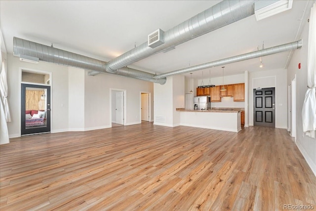 unfurnished living room featuring light wood-style flooring, visible vents, and baseboards