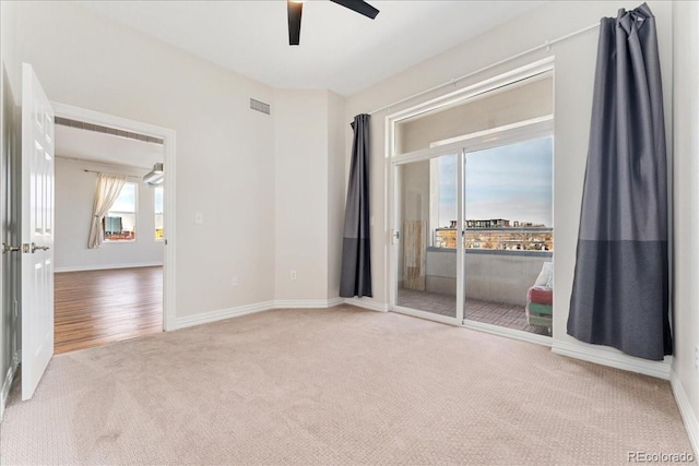 carpeted empty room featuring ceiling fan, visible vents, and baseboards