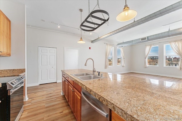 kitchen featuring tile countertops, light wood-style flooring, stainless steel appliances, a sink, and brown cabinetry