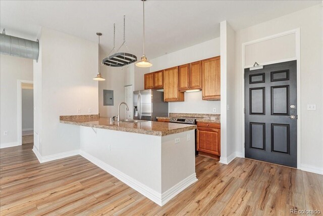 kitchen with a peninsula, light wood-type flooring, brown cabinets, and stainless steel refrigerator with ice dispenser