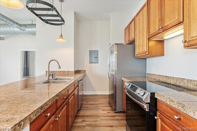 kitchen with tile countertops, appliances with stainless steel finishes, light wood-style floors, a sink, and electric panel