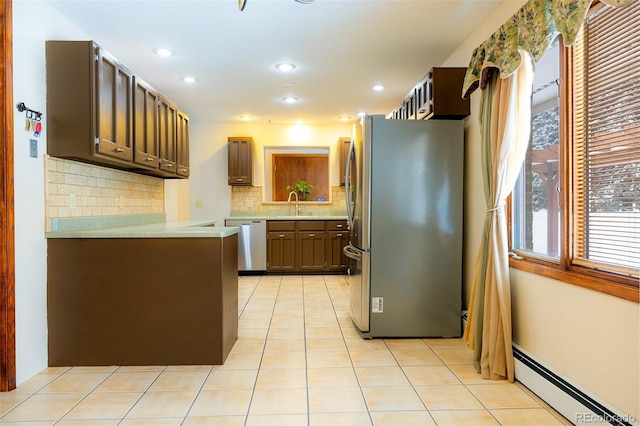 kitchen with sink, stainless steel appliances, tasteful backsplash, a baseboard heating unit, and light tile patterned floors