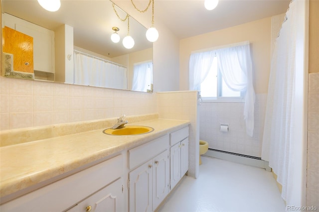 bathroom with baseboard heating, backsplash, toilet, vanity, and tile walls