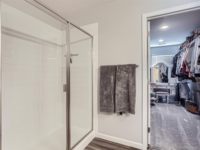 5995 Fencerow Pl, Brighton, CO 80601 - bathroom featuring a stall shower, a walk in closet, baseboards, and wood finished floors