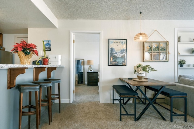 carpeted dining space with a textured ceiling