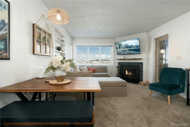 living room featuring built in features, carpet, a fireplace, and a textured ceiling