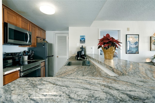 kitchen with electric stove, sink, light stone countertops, and a textured ceiling