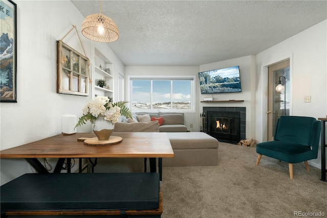 living room featuring a textured ceiling, a tiled fireplace, and carpet flooring