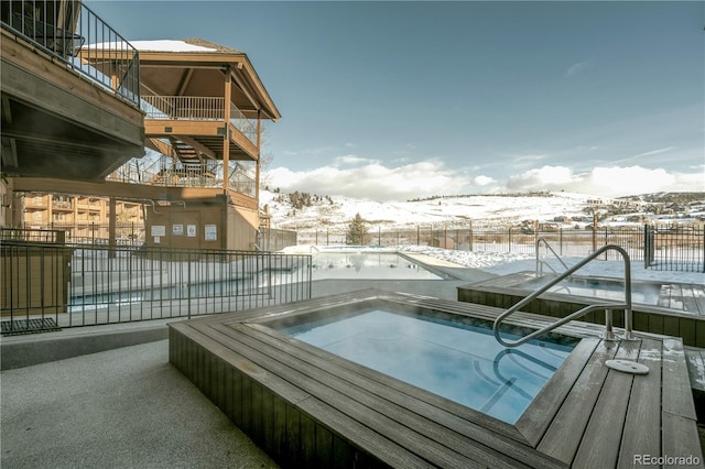 snow covered pool with a mountain view and fence