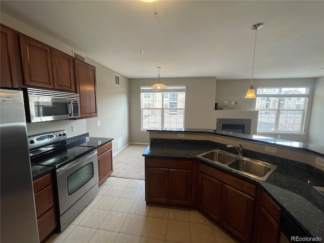 17346 Nature Walk Trl Unit 201, Parker, CO 80134 - kitchen featuring stainless steel appliances, a sink, decorative light fixtures, and a glass covered fireplace