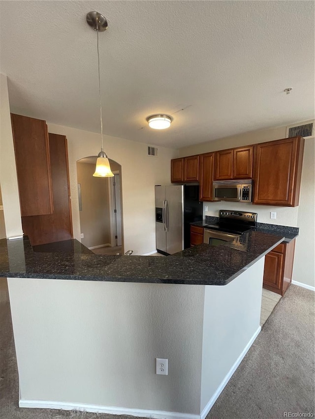 17346 Nature Walk Trl Unit 201, Parker, CO 80134 - kitchen featuring appliances with stainless steel finishes, arched walkways, a peninsula, brown cabinetry, and dark stone countertops