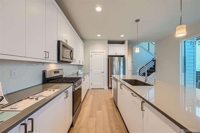 kitchen with pendant lighting, sink, appliances with stainless steel finishes, white cabinets, and decorative backsplash