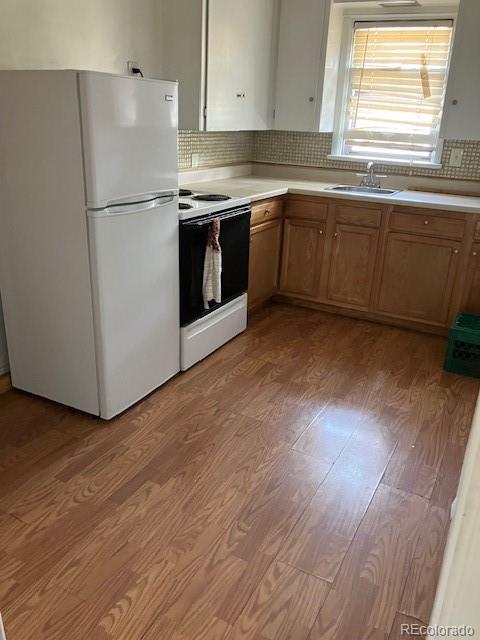 kitchen with decorative backsplash, sink, wood-type flooring, and white appliances