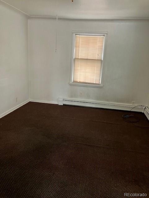 empty room with carpet floors and a baseboard heating unit