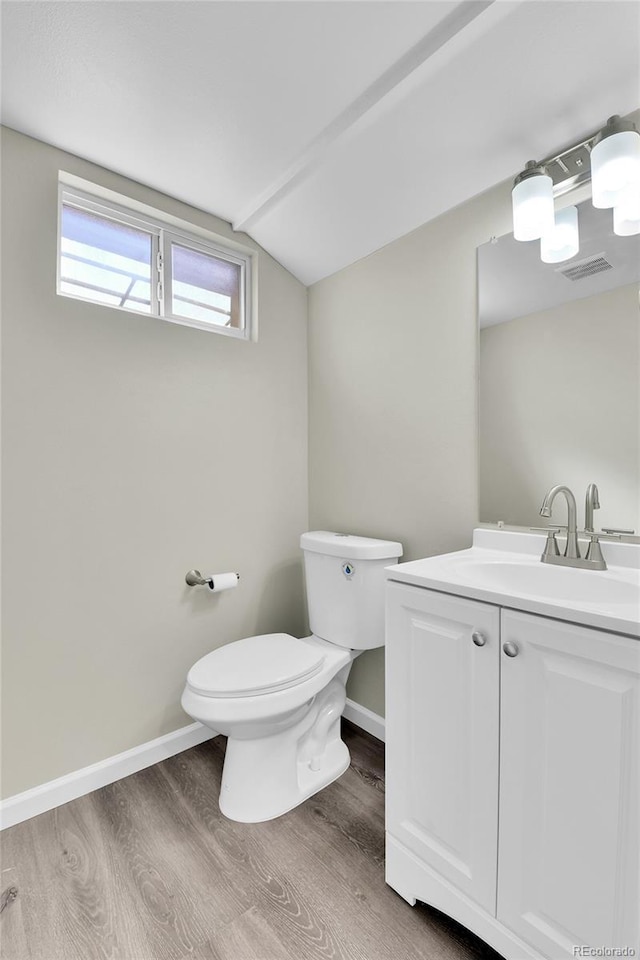 bathroom with vanity, wood-type flooring, vaulted ceiling, and toilet