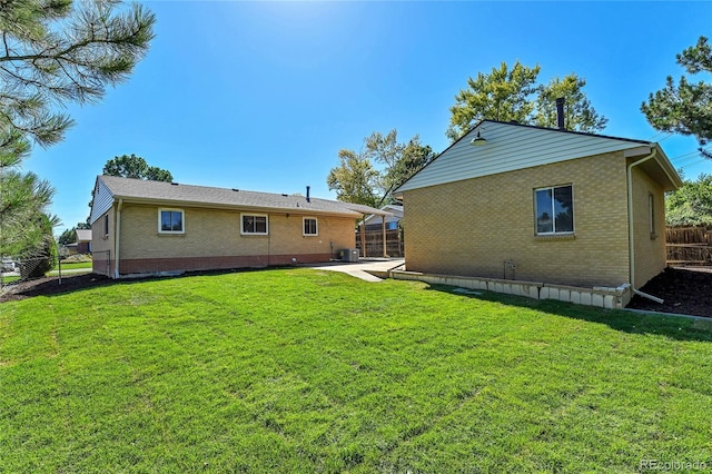 rear view of property featuring a lawn and central air condition unit