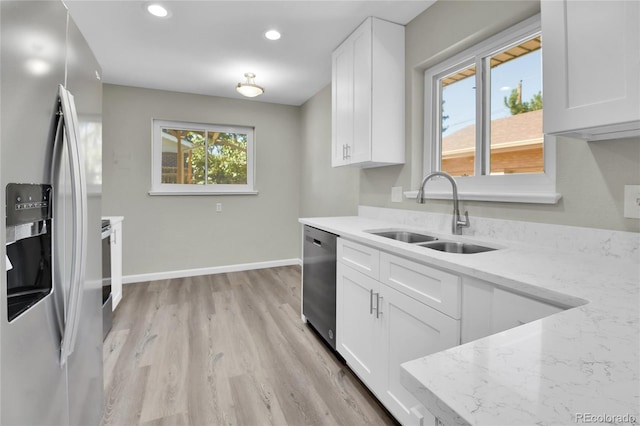 kitchen with white cabinetry, sink, stainless steel appliances, light stone counters, and light hardwood / wood-style flooring