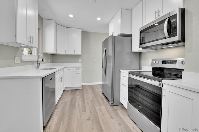 kitchen with light hardwood / wood-style floors, white cabinetry, sink, and appliances with stainless steel finishes