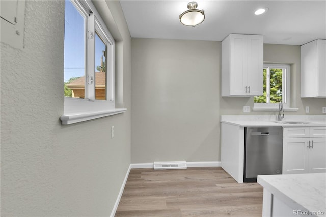 kitchen with dishwasher, white cabinetry, sink, and light hardwood / wood-style flooring