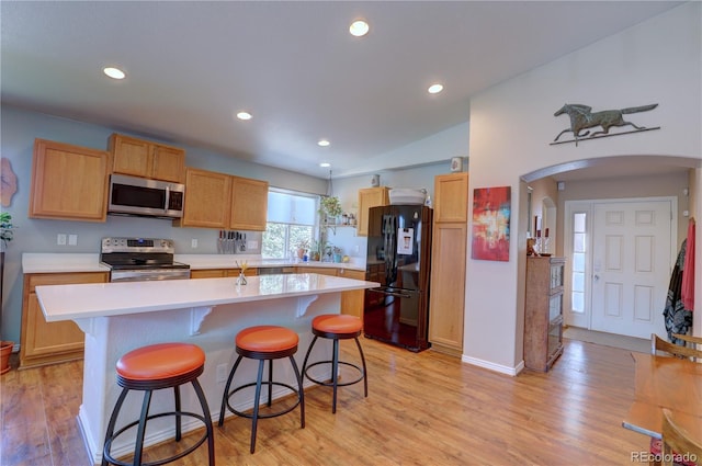 20194 Robins Dr, Denver, CO 80249 - kitchen featuring appliances with stainless steel finishes, arched walkways, light countertops, a kitchen breakfast bar, and light wood-style flooring