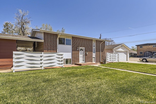 raised ranch with a front lawn, fence, brick siding, an attached garage, and driveway