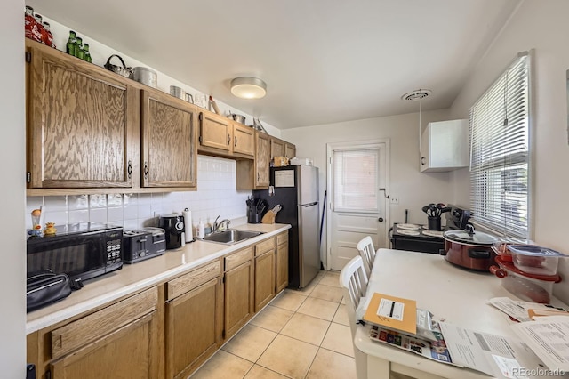 kitchen featuring black microwave, a sink, a wealth of natural light, and light countertops