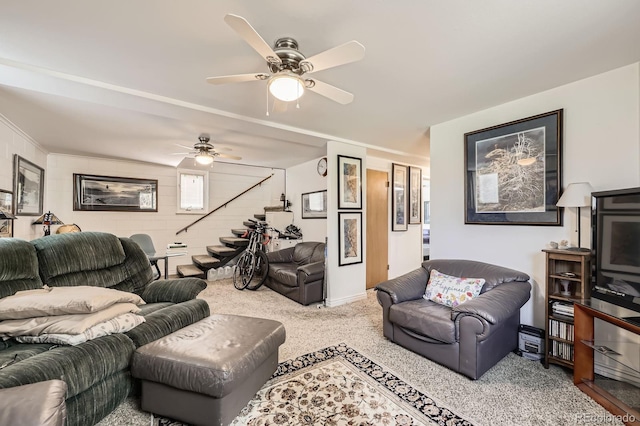 carpeted living area featuring stairway, baseboards, and ceiling fan
