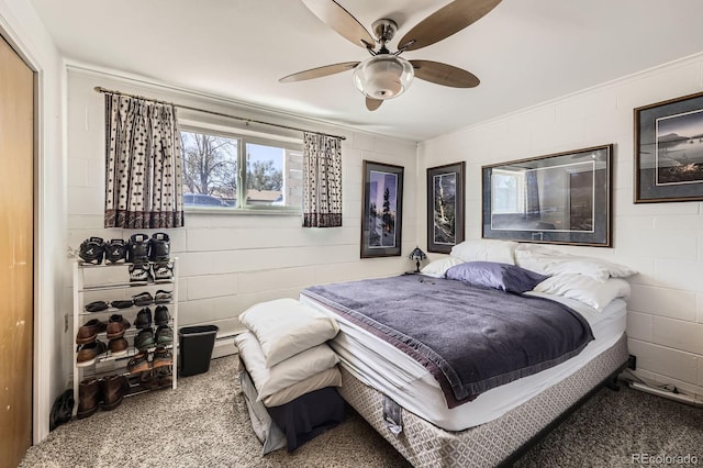 carpeted bedroom featuring ornamental molding, ceiling fan, and concrete block wall