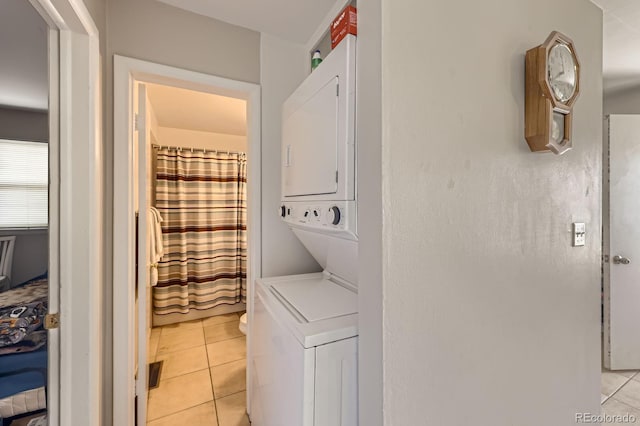 washroom with stacked washer and clothes dryer, light tile patterned flooring, and laundry area