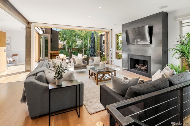 living room featuring a fireplace, light hardwood / wood-style flooring, and floor to ceiling windows