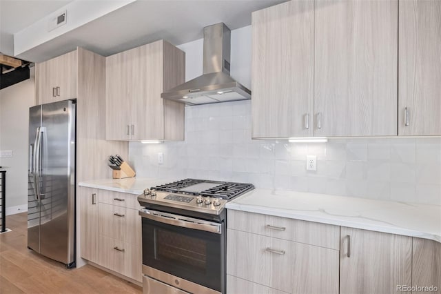 kitchen featuring decorative backsplash, appliances with stainless steel finishes, light brown cabinets, and wall chimney range hood