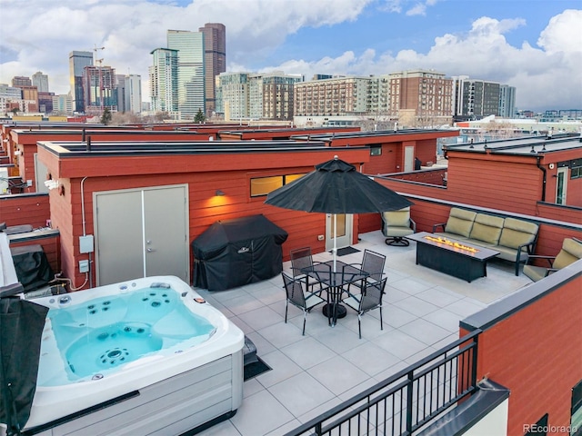 view of patio featuring a view of city, a hot tub, a grill, and an outdoor fire pit