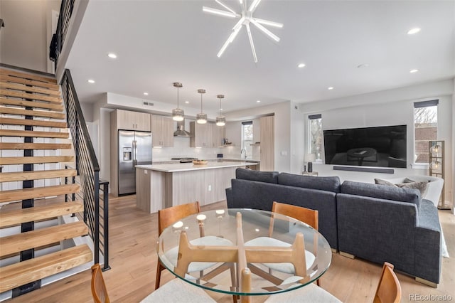 dining space with light wood finished floors, stairs, and recessed lighting