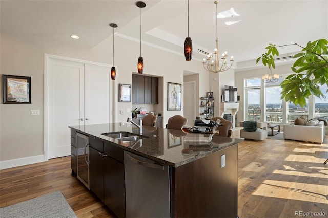 kitchen with wood-type flooring, sink, dark brown cabinets, stainless steel dishwasher, and an inviting chandelier