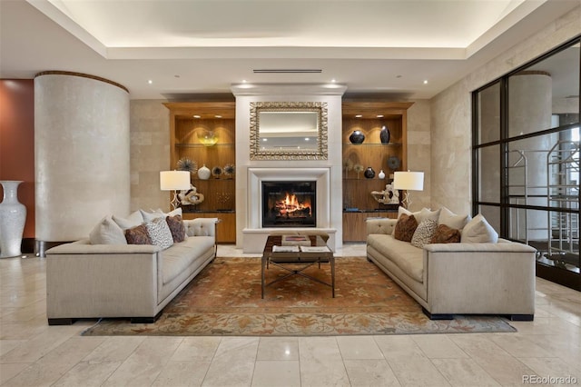 living room featuring a fireplace, built in features, and a raised ceiling