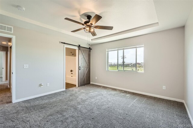 7263 Horsechestnut St, Wellington, CO 80549 - unfurnished bedroom with a barn door, carpet, a tray ceiling, baseboards, and ensuite bath
