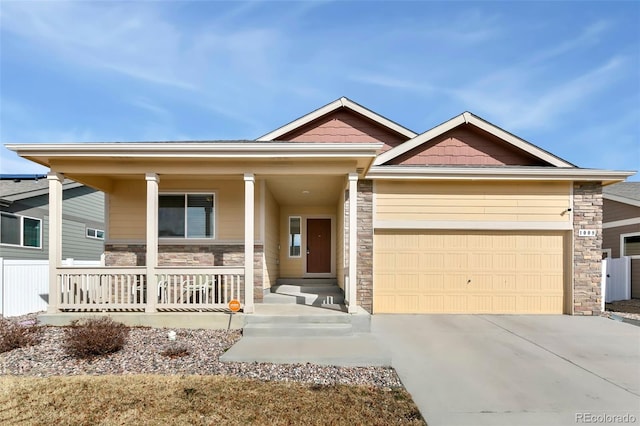 craftsman-style house featuring driveway, stone siding, a garage, and a porch